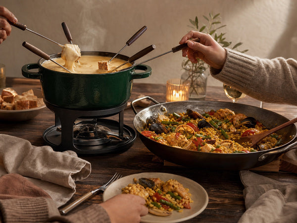 Cast iron fondue set and Spanish paella pan shared around a winter dining table
