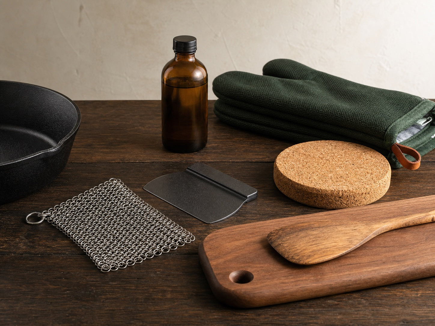 Chainmail scrubber, pan scraper, seasoning oil, trivet, oven mitt and wooden utensils for cast iron care